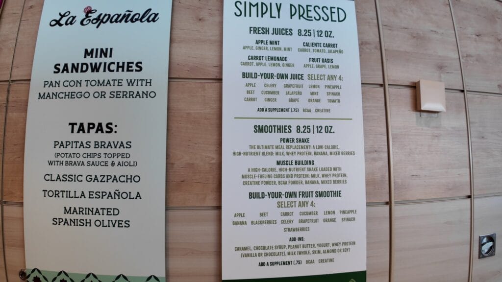 The La Espanola and Simply Pressed menu boards in the AquaDome Market, with fresh juices and smoothies priced at 8.25 for 12 ounces.