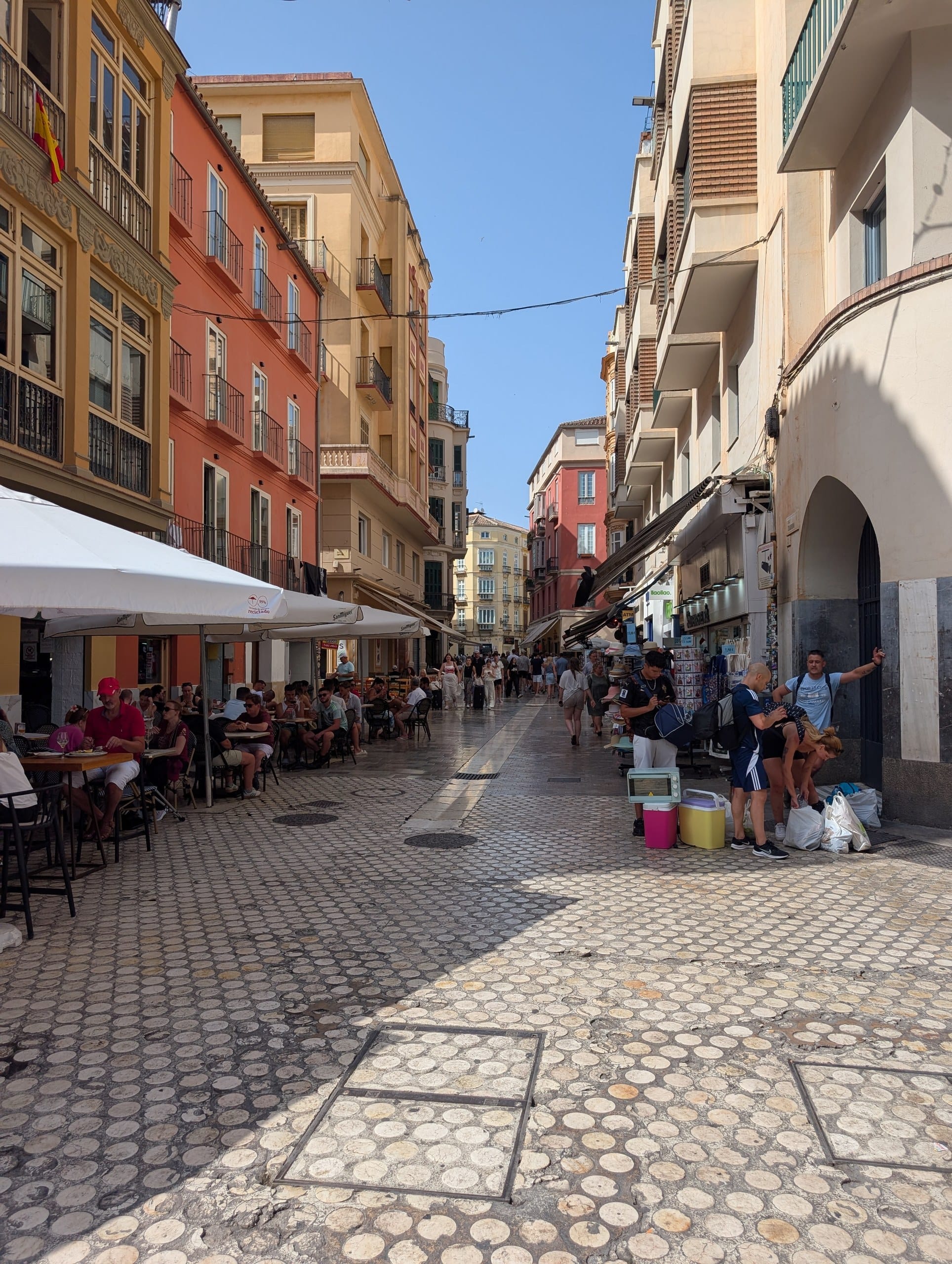 Narrow pedestrian street in the Malaga old town with awnings and terrace tables