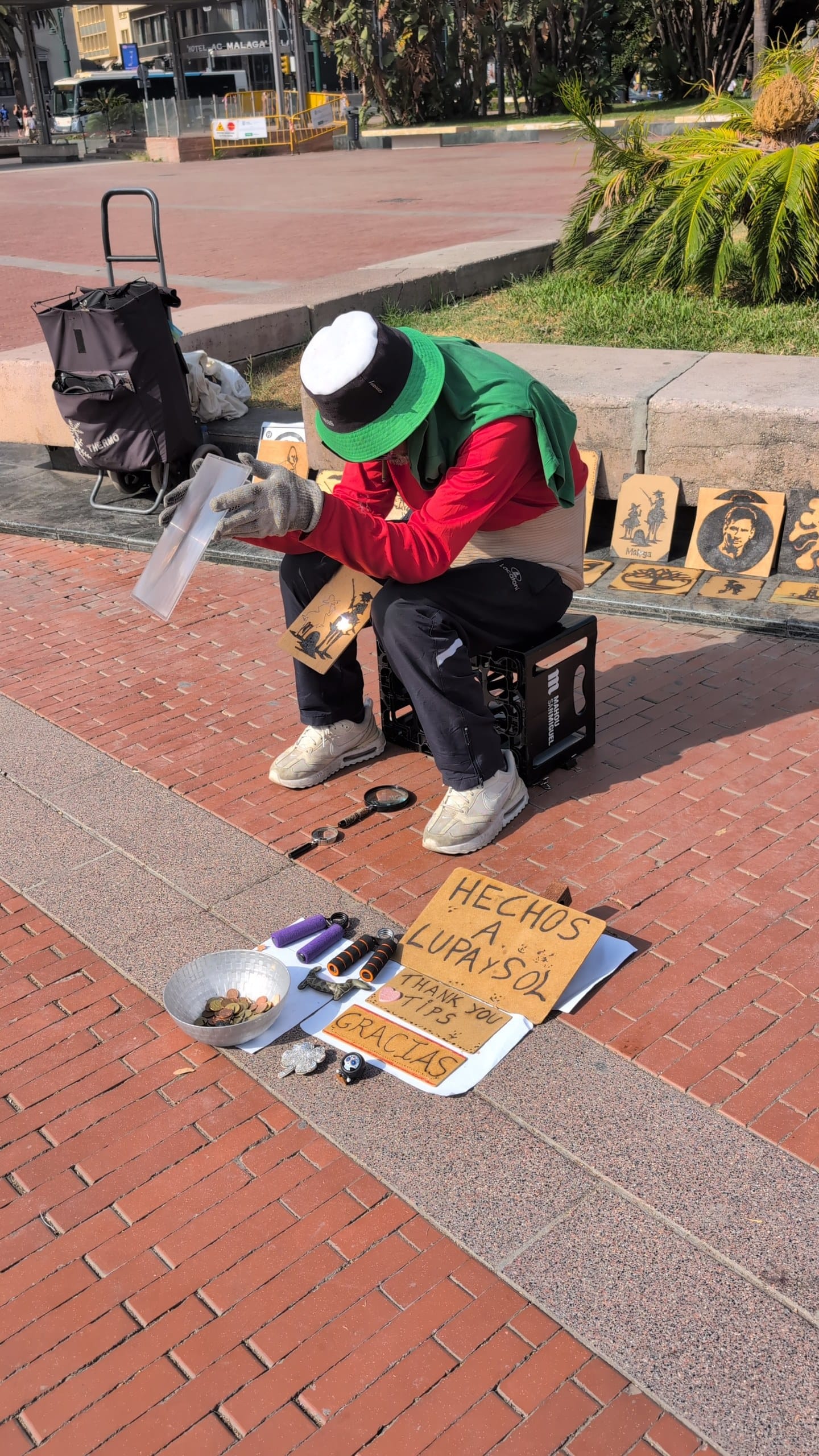 Street artist in Malaga burning designs into wood using a magnifying glass and sunlight