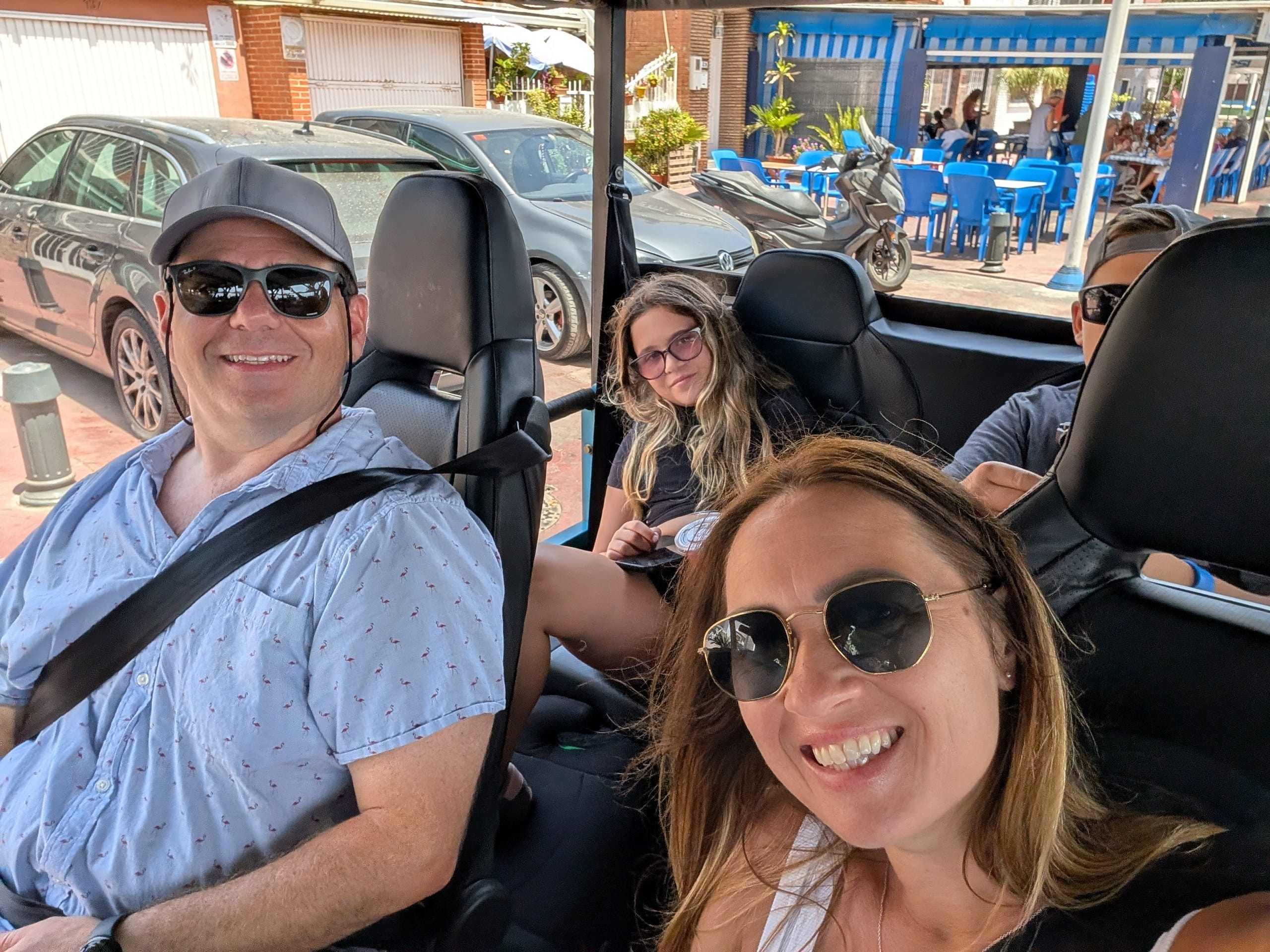 Family of four riding in an open sided electric tuk tuk in Malaga