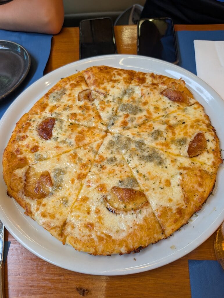 A four cheese pizza with a cheese pull at Rincón Marino