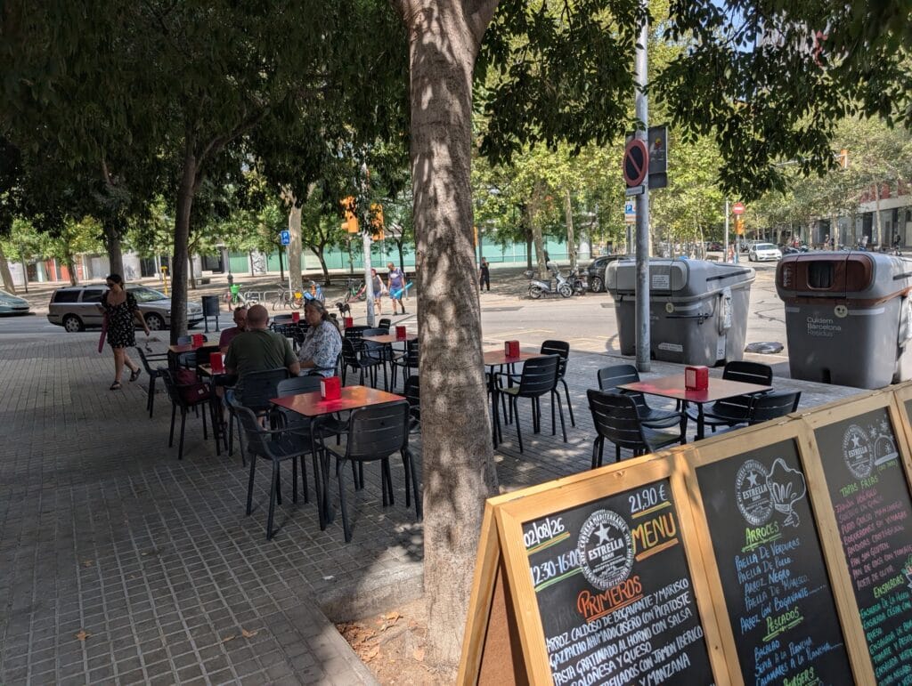 Sidewalk terrace tables under the trees outside Rincón Marino in Poblenou