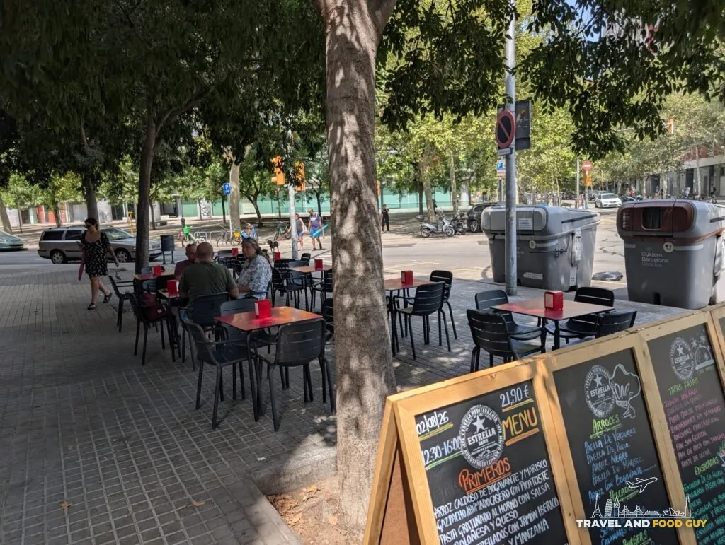Sidewalk terrace tables under the trees outside Rincón Marino in Poblenou