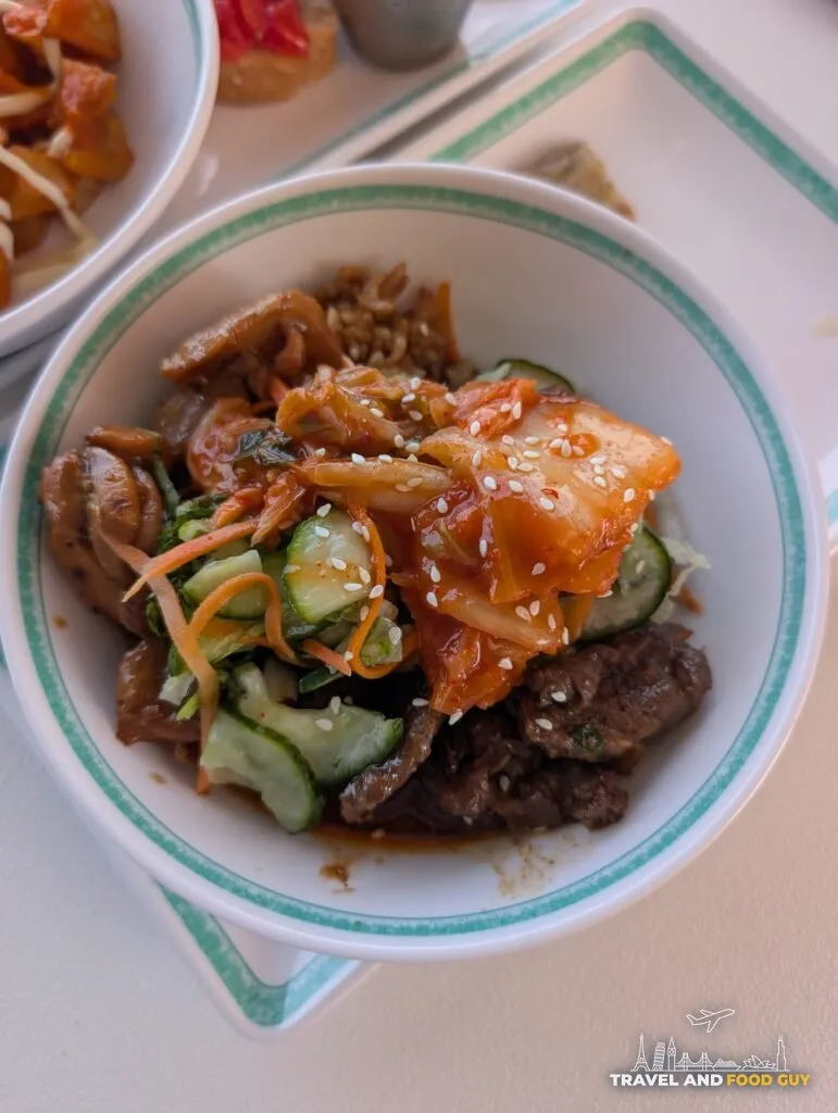A Seoulmate bulgogi bowl on Legend of the Seas, marinated beef and rice under kimchi, cucumber, pickled carrot and white sesame.