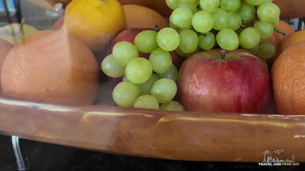 A wooden bowl of oranges, grapes, apples and lemons on the Simply Pressed counter in the AquaDome Market.