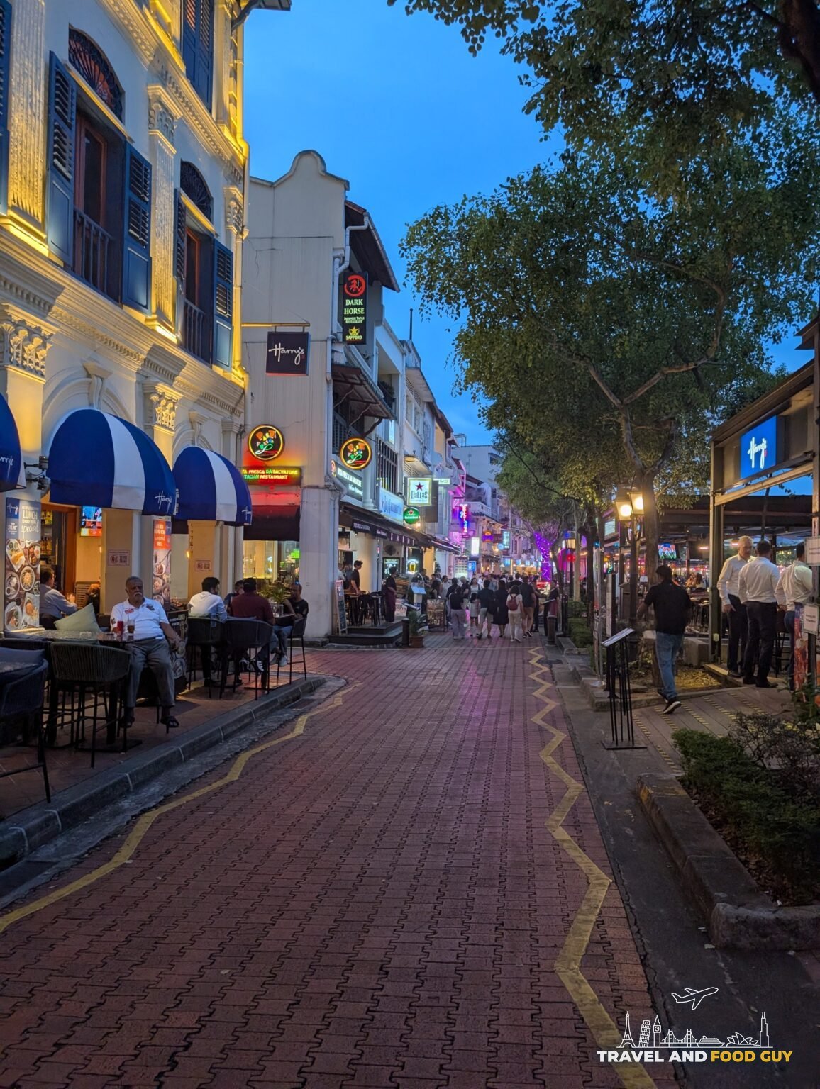 Colonial shophouse alley in the Bugis and Bras Basah area at blue hour with restaurants and bars filling up