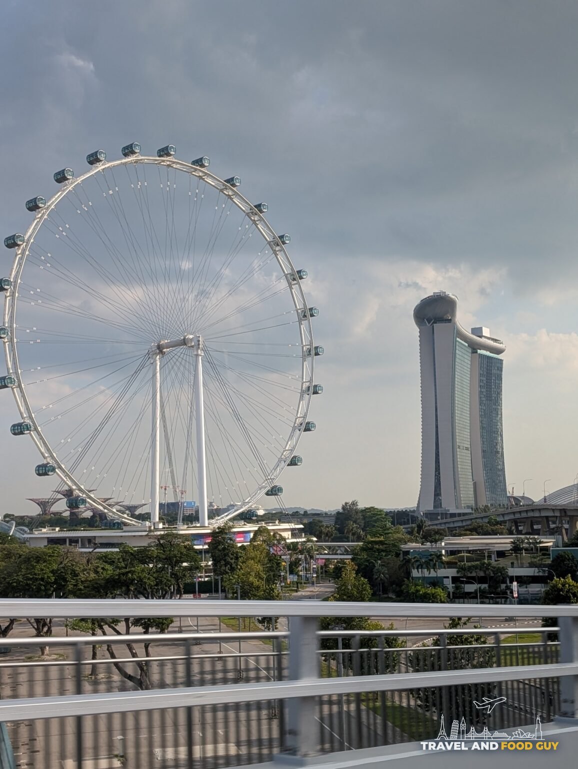 The Singapore Flyer observation wheel and the lotus-shaped ArtScience Museum with a corner of Marina Bay Sands framed from an elevated walkway