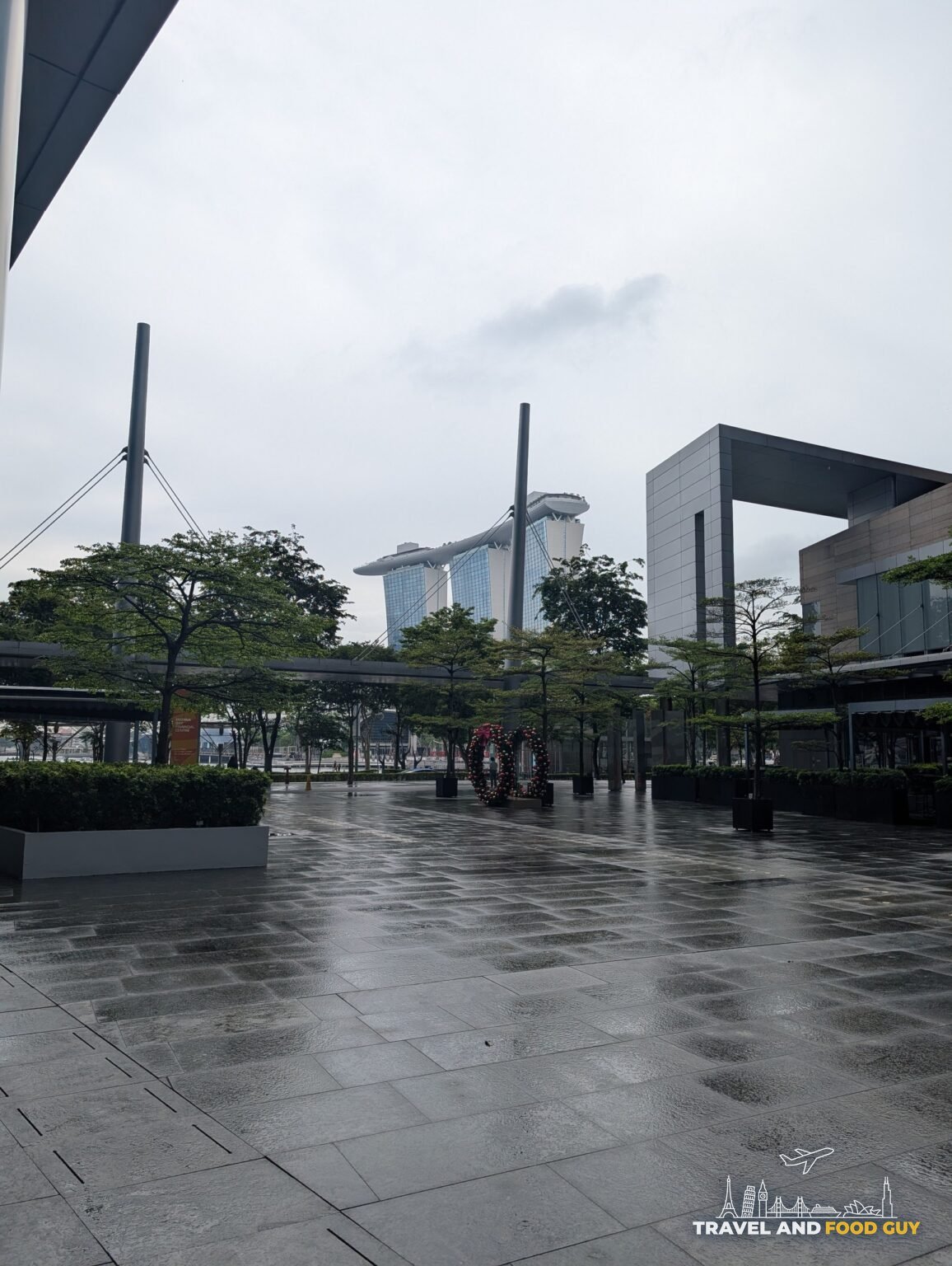 Wet plaza between the Esplanade concert halls with Marina Bay Sands three towers rising in the background