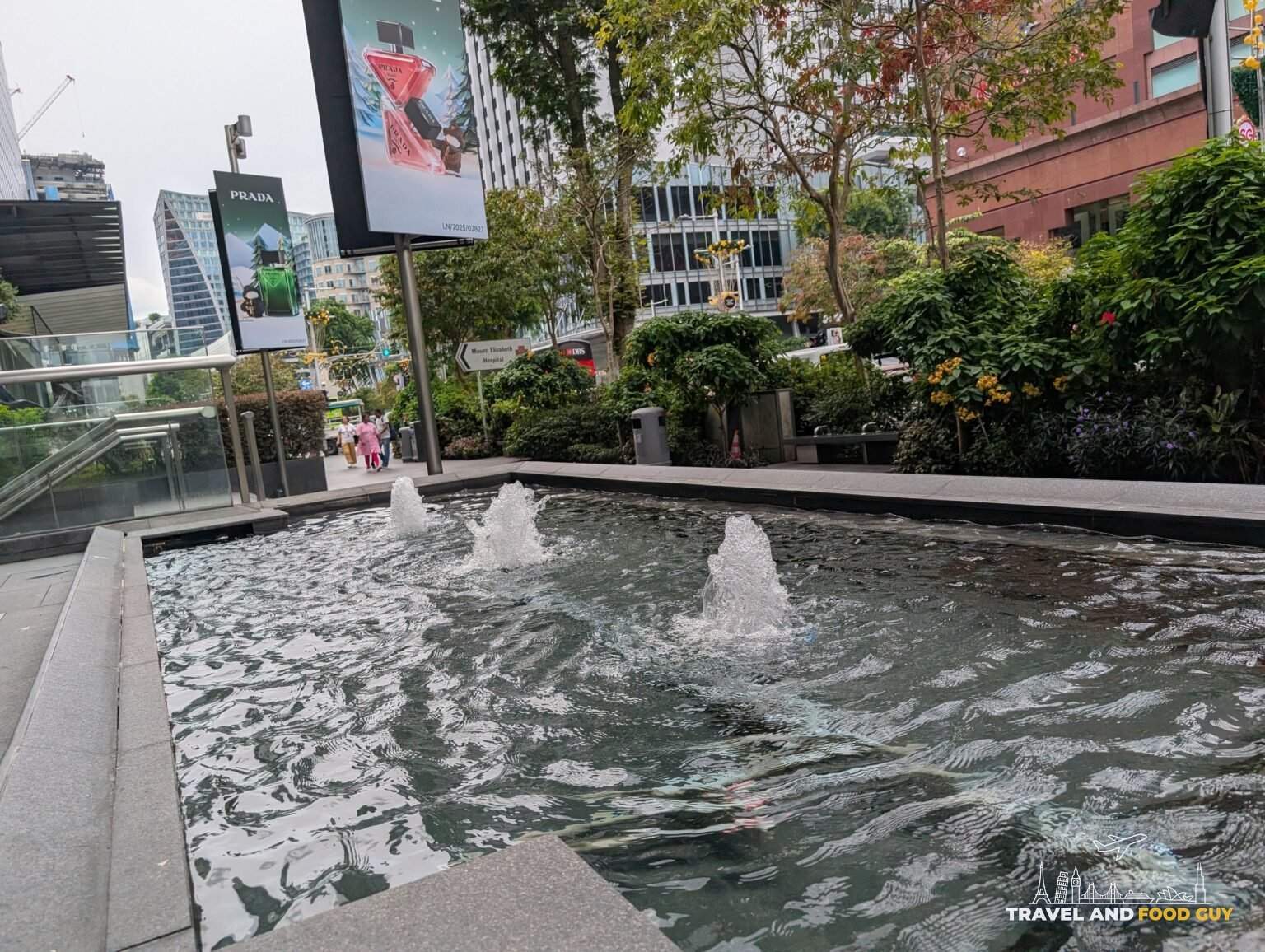 Sidewalk fountain along Orchard Road in front of Prada with tropical planting behind it, Singapore
