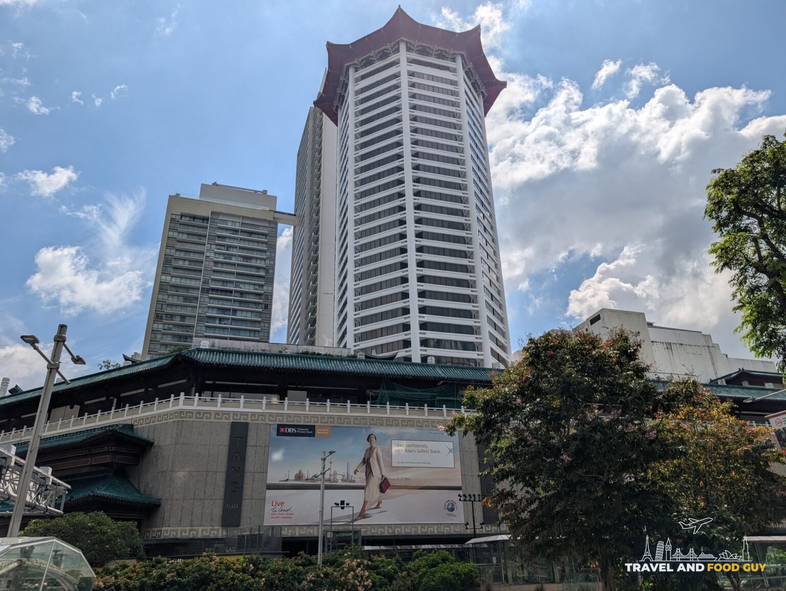 The red pagoda-roofed tower of a hotel on Orchard Road framed against Singapore blue sky and low white clouds