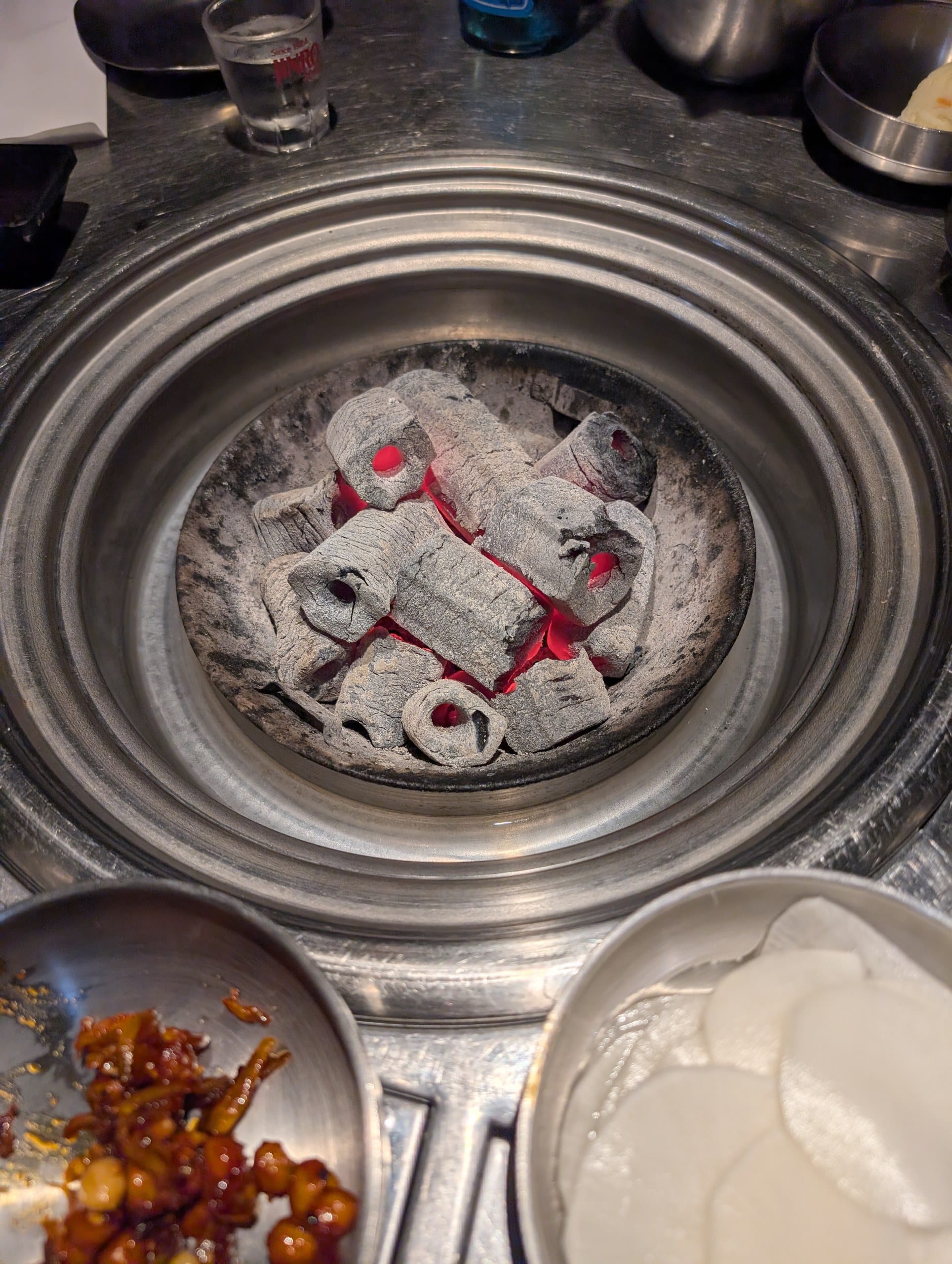 Live charcoal in the recessed table well at Tanjong Hwaro