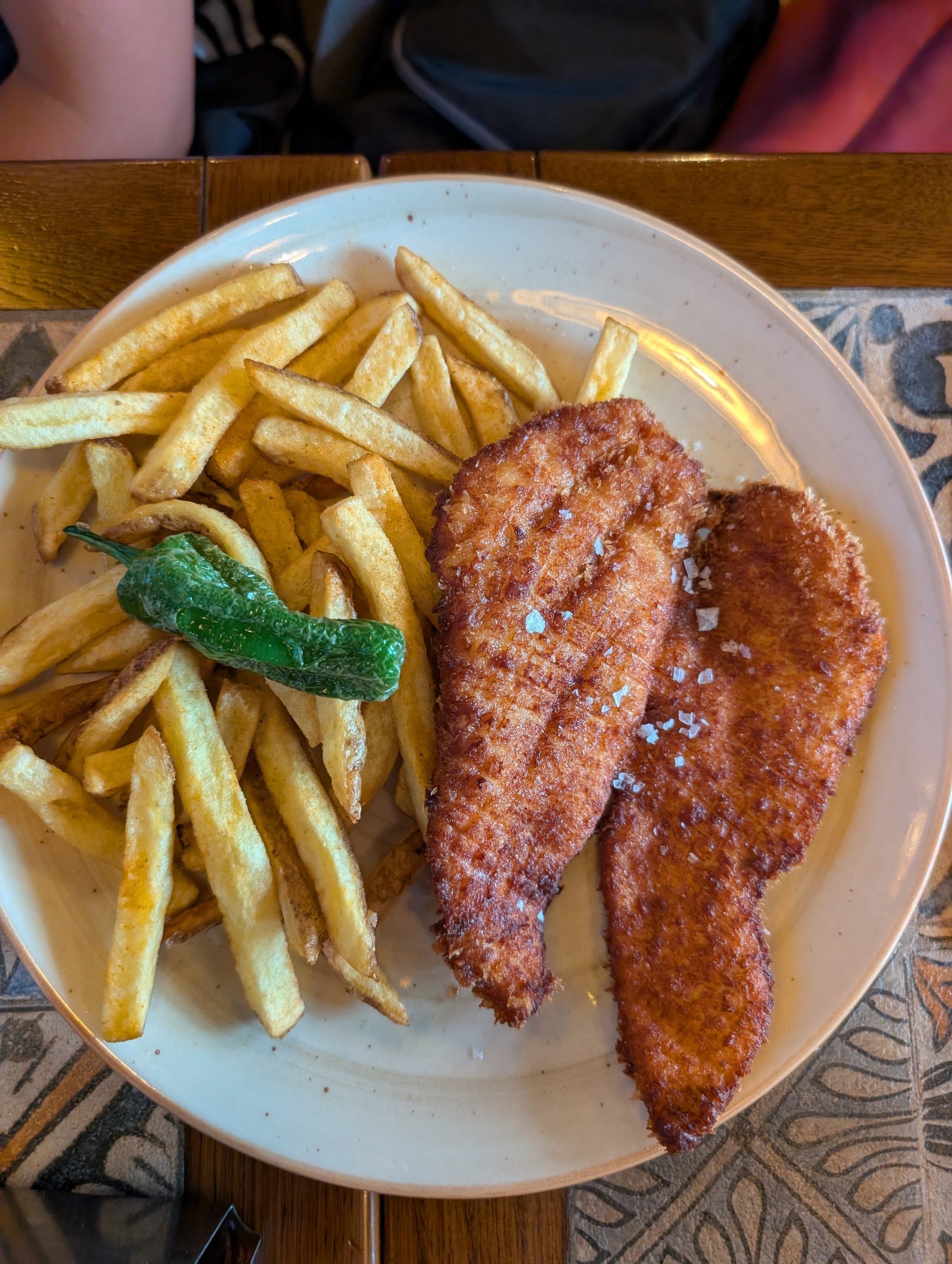 Two breaded chicken fillets with fries and a whole fried green pepper at Tapas San Miguel in Barcelona