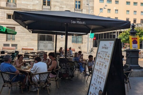 Tables under San Miguel branded parasols on Placa Sant Miquel in the Gothic Quarter of Barcelona