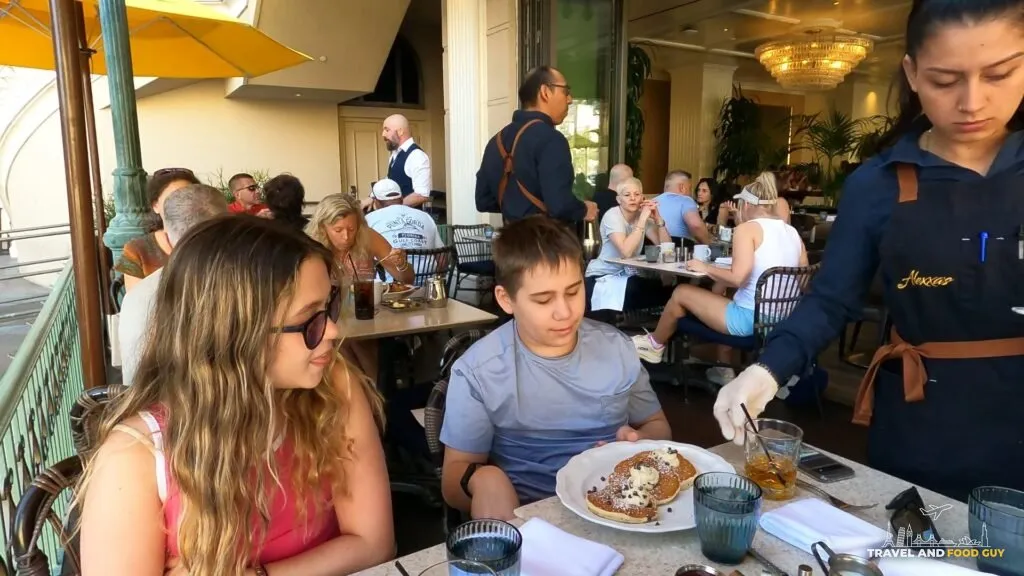 The kids at breakfast on the patio at Alexxa's at Paris Las Vegas with a plate of pancakes on the table