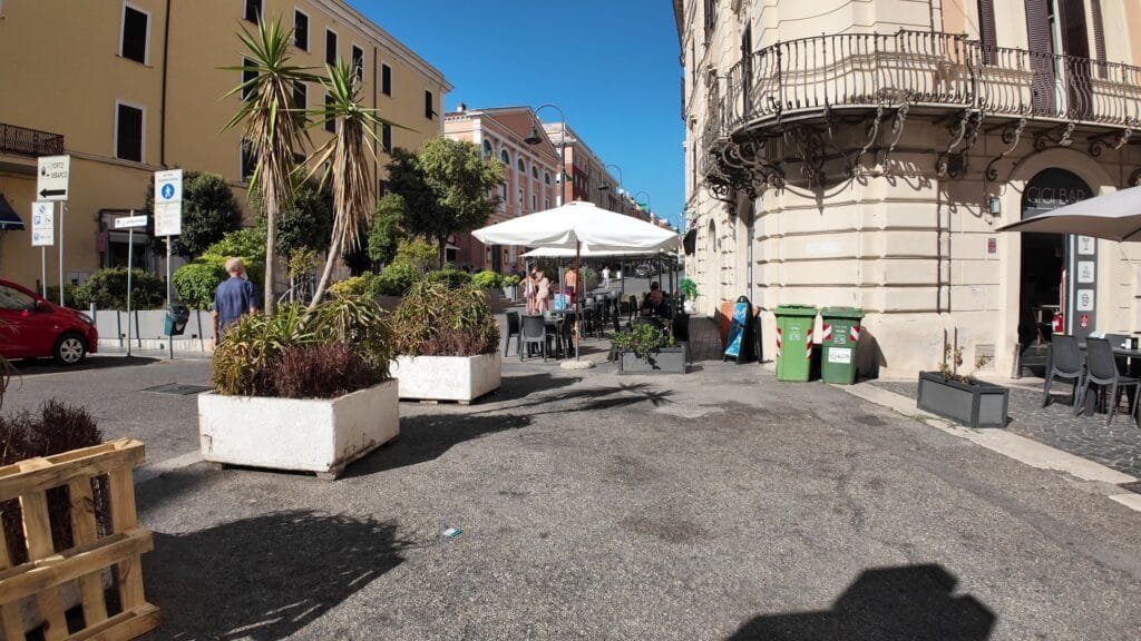 A square in the Civitavecchia old town with cafe umbrellas and shopfronts