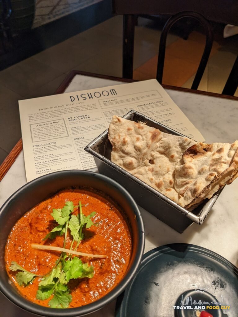 A bowl of curry topped with cilantro and ginger next to naan on a Dishoom menu at Dishoom Covent Garden.