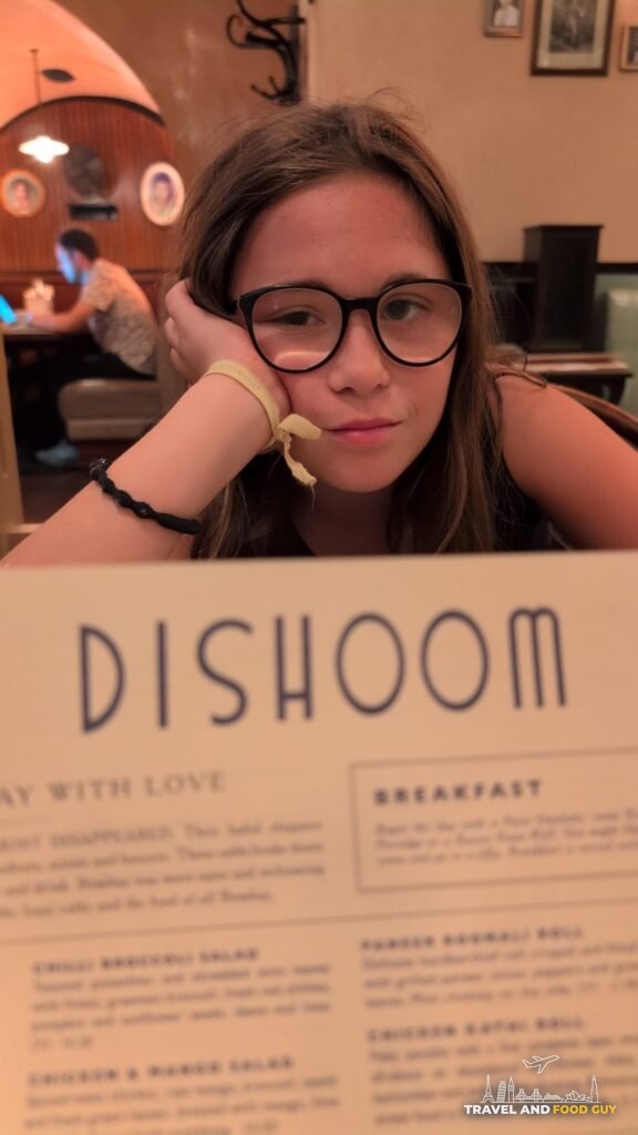 Emily at the table behind a Dishoom menu at Dishoom Covent Garden.