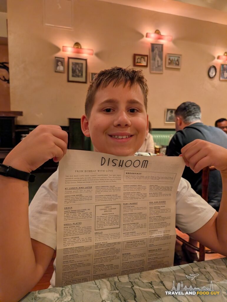 Josh holding up the Dishoom menu at Dishoom Covent Garden.