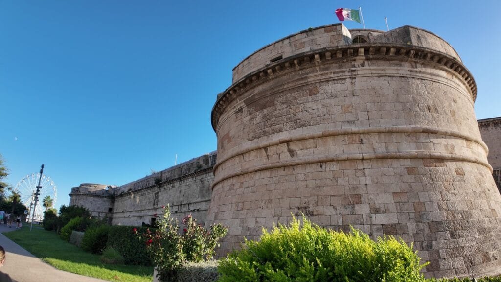 Low angle view of the round bastion of Forte Michelangelo with the Italian flag flying on top