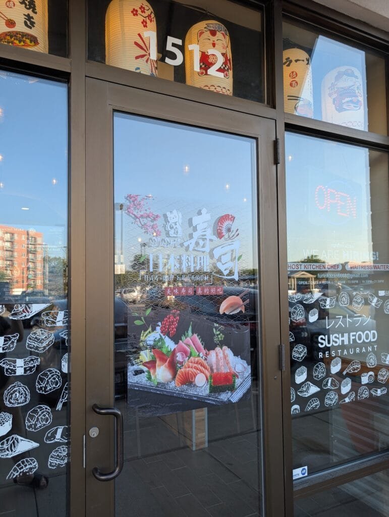 The front door at 1512 Market Street, with paper lanterns above it and the hours decal on the glass.