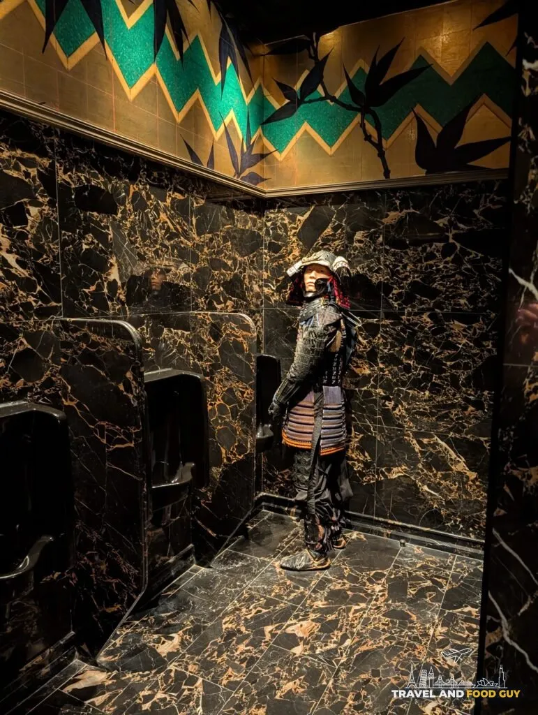 A samurai mannequin standing between the urinals in the men's room at The Ivy Asia St Paul's, facing the door.