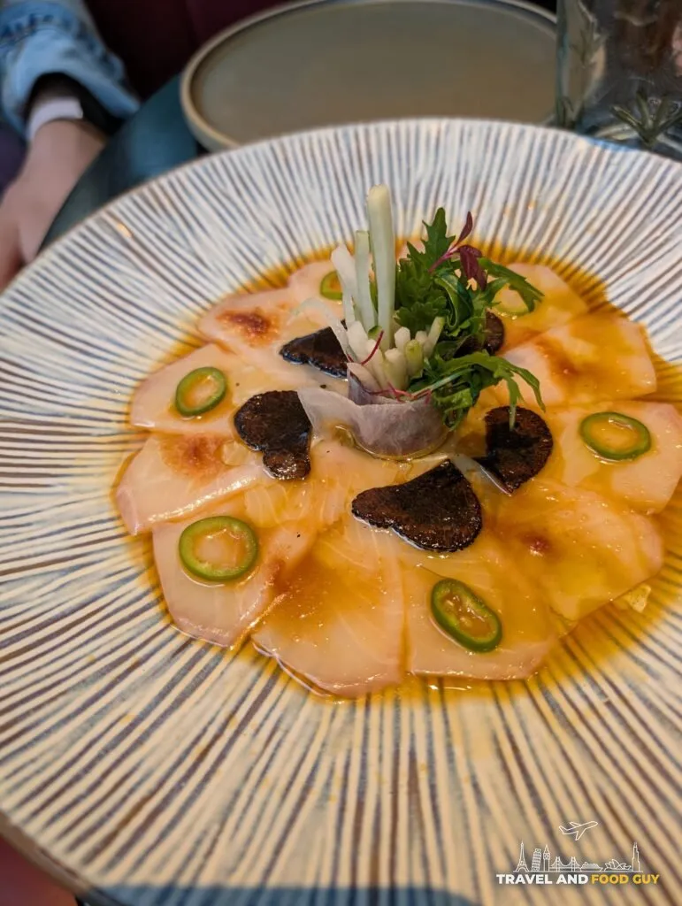 Yellowtail sashimi with truffle and jalapeno slices in a light sauce at The Ivy Asia St Paul's.
