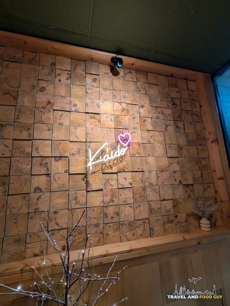 A wall of end grain wood blocks with a pink neon Kaido sign inside the dining room.