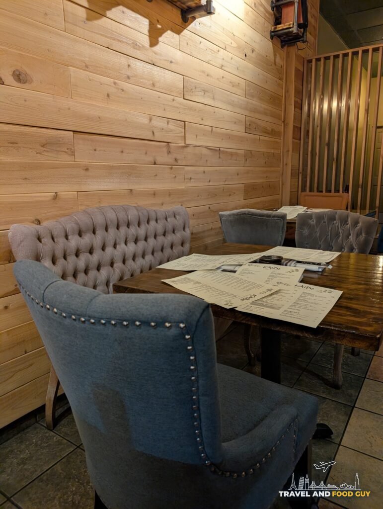 A tufted banquette and upholstered chairs against Kaido's wood plank walls.