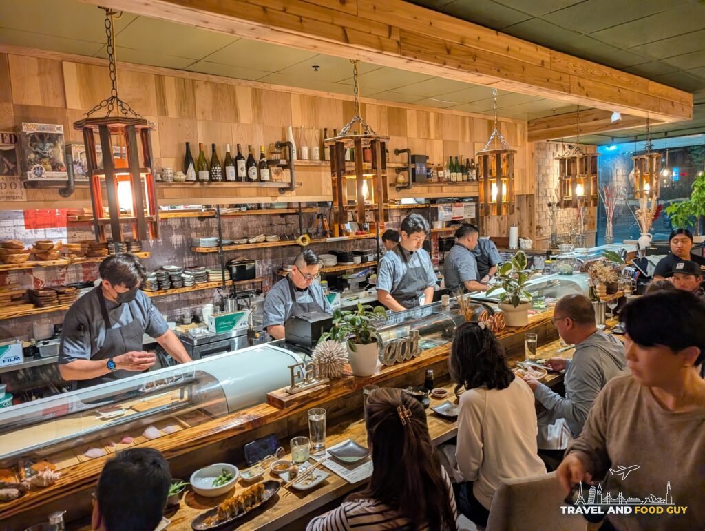 Sushi chefs working behind Kaido's bar while guests eat at the counter.