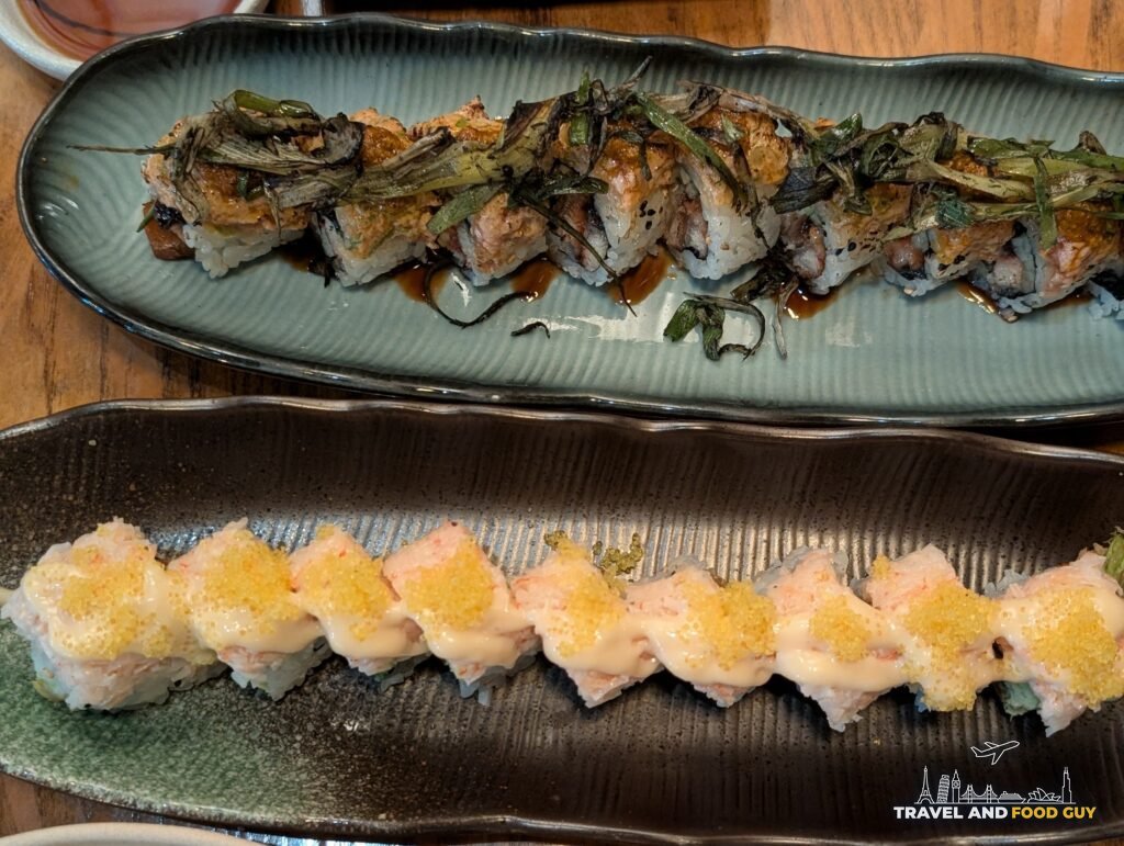 Kaido's Azure Dragon roll with charred scallion next to the Crabby Crab roll with yellow tobiko.