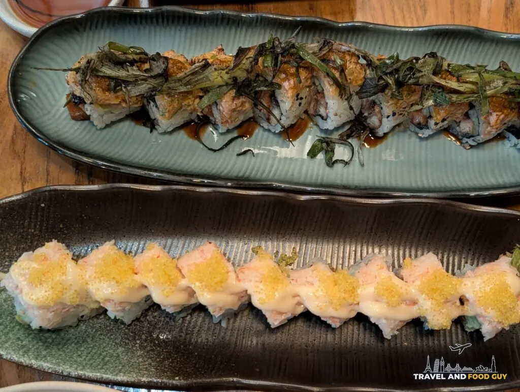 Kaido's Azure Dragon roll with charred scallion next to the Crabby Crab roll with yellow tobiko.