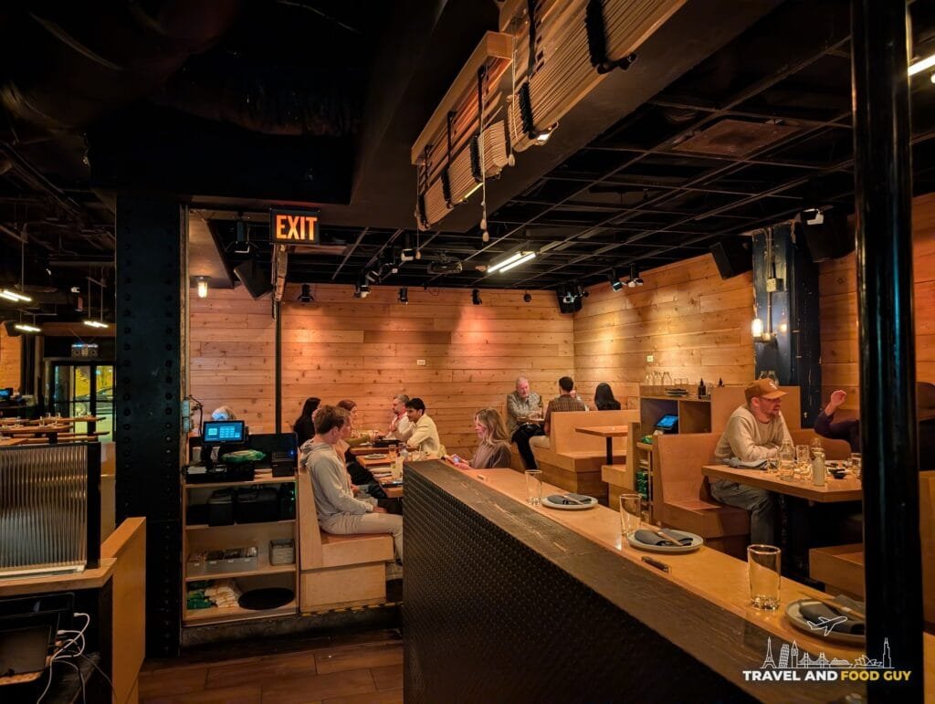 A wood paneled back dining room at Sushi-San with booths and a long counter.
