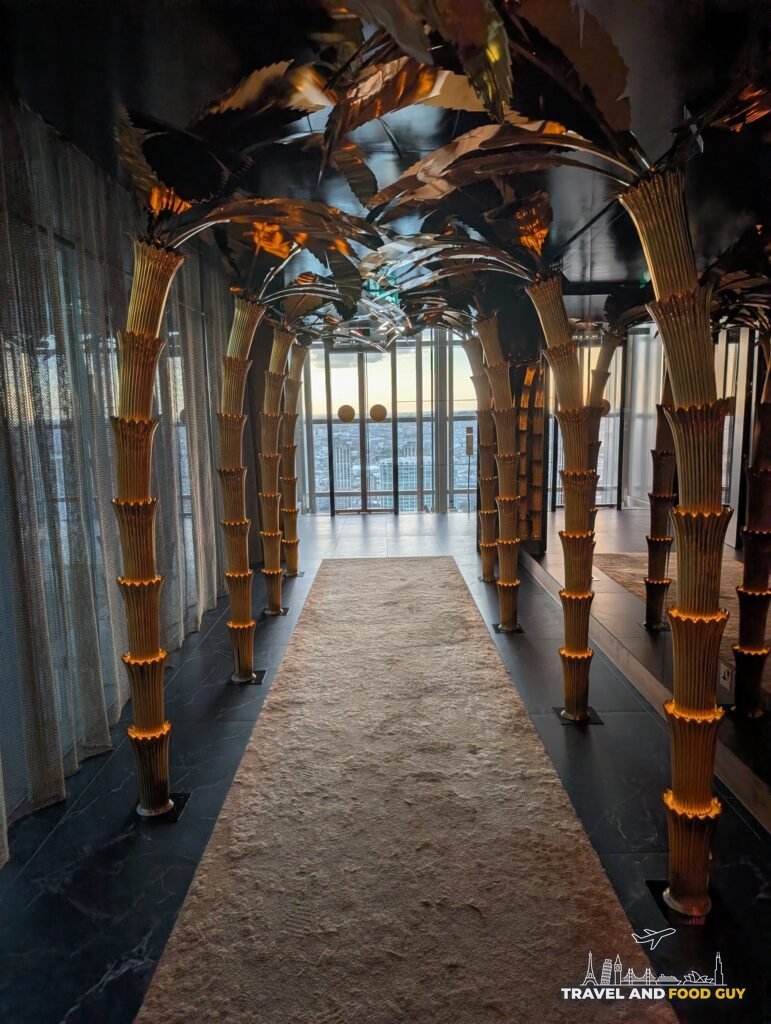 The gold palm corridor at SUSHISAMBA London with the windows and the City of London at the far end.