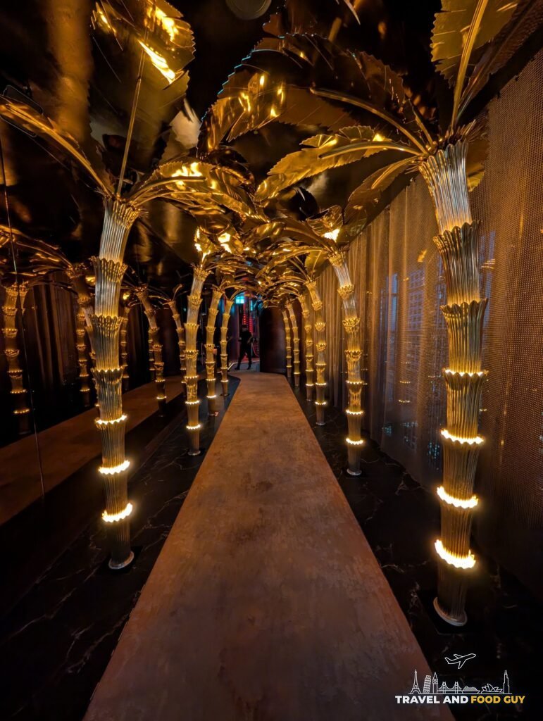 The gold palm corridor at SUSHISAMBA London at night, lit gold.