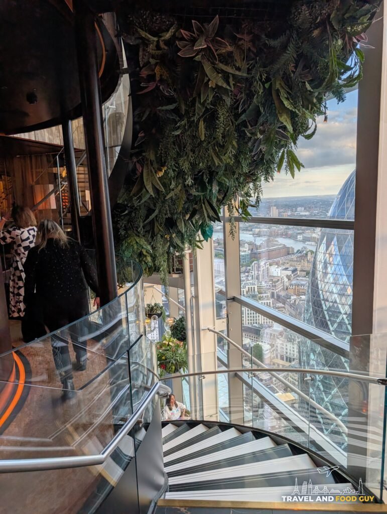 The spiral staircase at SUSHISAMBA London with the Gherkin framed in the tall windows behind it.