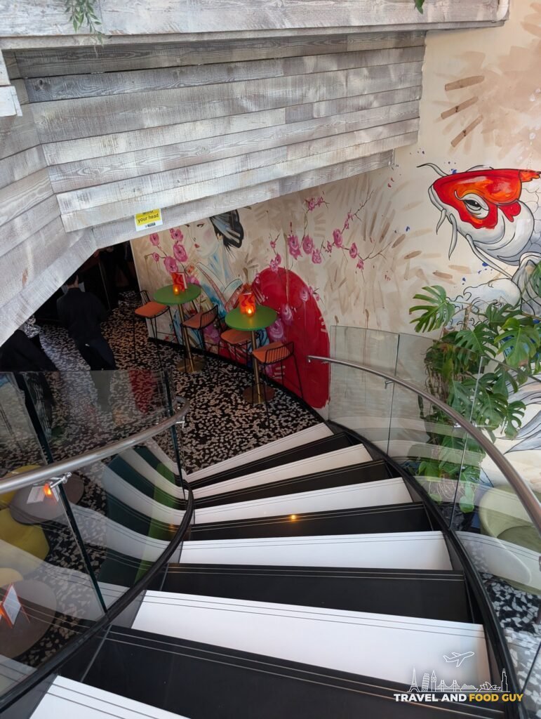 The spiral staircase at SUSHISAMBA London curving down past a koi mural.