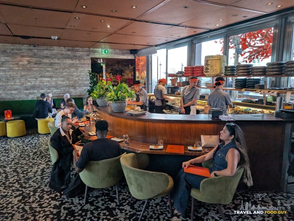 The sushi counter at SUSHISAMBA London with chefs working and every seat taken.
