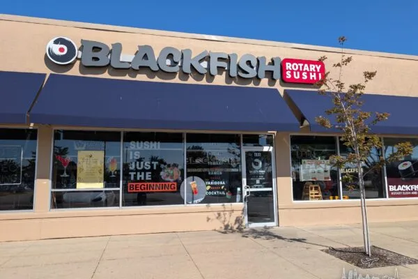 The Blackfish Rotary Sushi storefront in a Buffalo Grove strip mall, with a navy awning and a red Rotary Sushi sign.