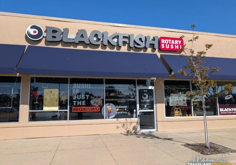 The Blackfish Rotary Sushi storefront in a Buffalo Grove strip mall, with a navy awning and a red Rotary Sushi sign.