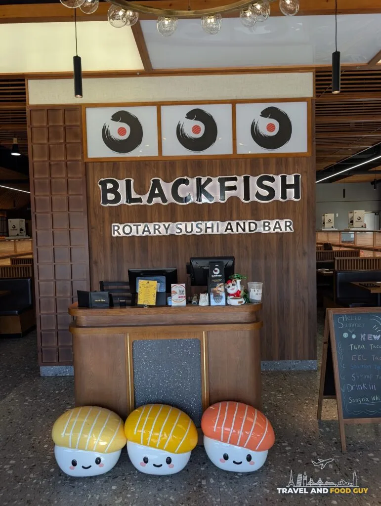 The host stand at Blackfish Rotary Sushi and Bar with three giant sushi plushies sitting on the floor in front of it.