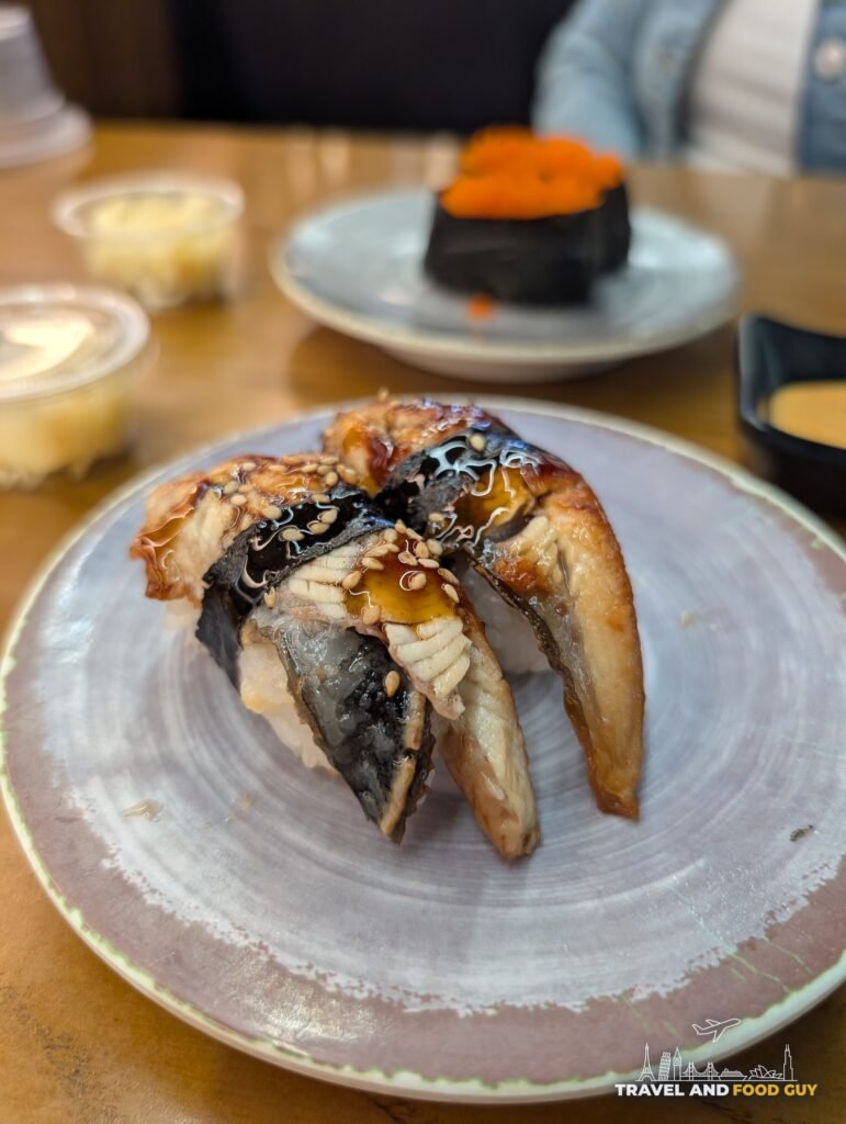 Two pieces of eel nigiri with eel sauce on a gray plate.