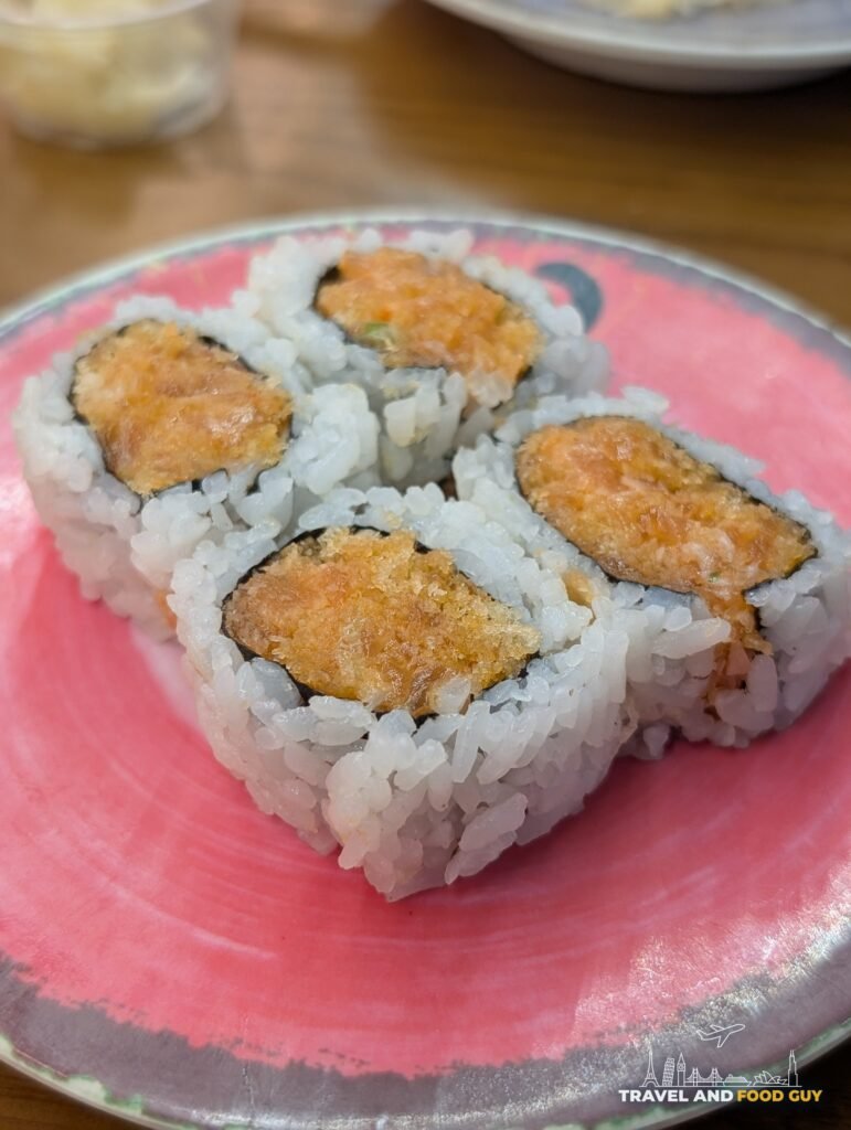 Four pieces of spicy salmon roll on a pink plate at Blackfish Rotary Sushi.