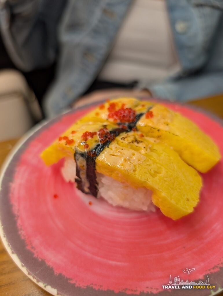 Two pieces of tamago nigiri, lightly seared, with spicy mayo and masago on top.