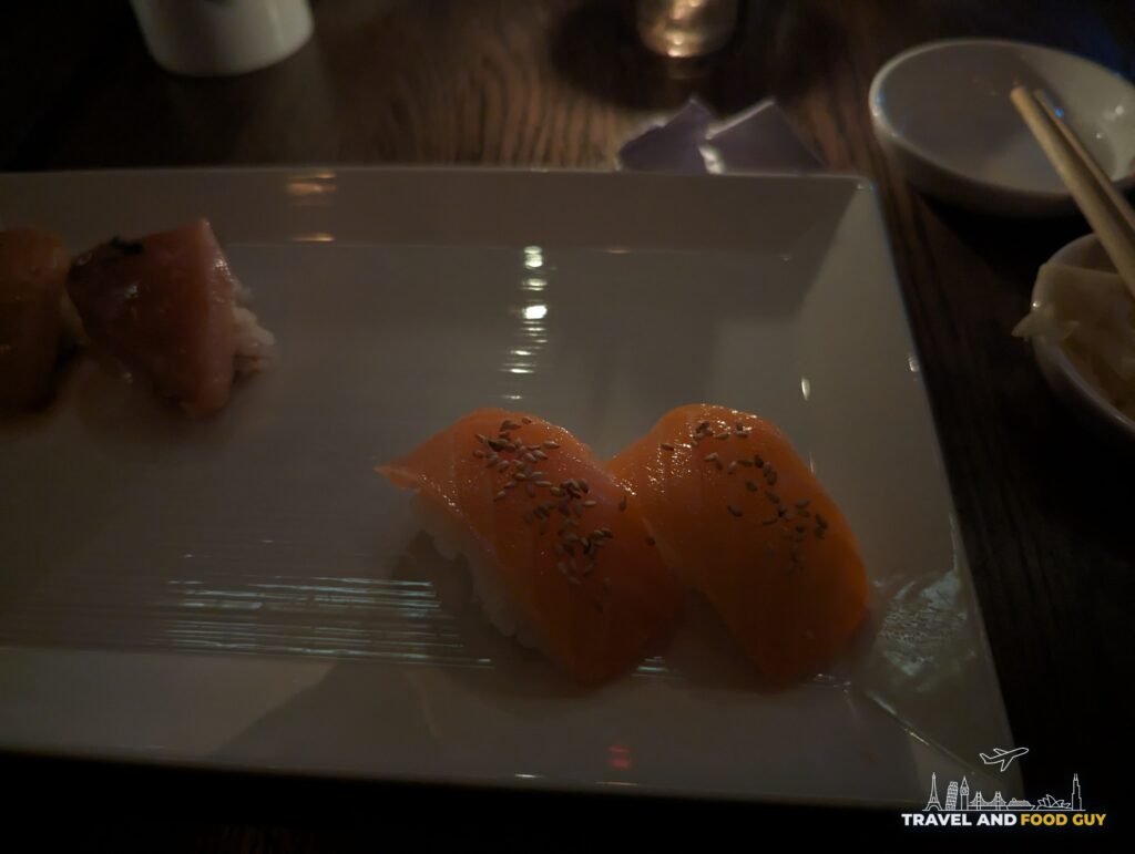 Two pieces of salmon nigiri topped with toasted sesame on a white plate at SUGARFISH Beverly Hills.