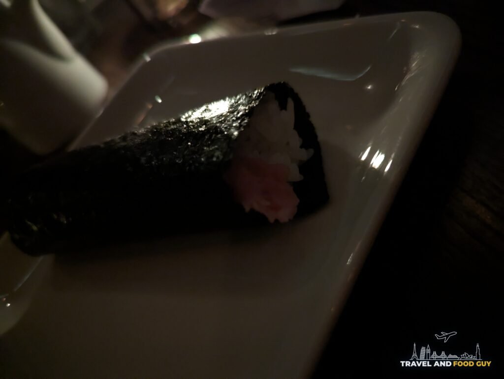 A toro hand roll wrapped in crisp seaweed on a white plate at SUGARFISH Beverly Hills.