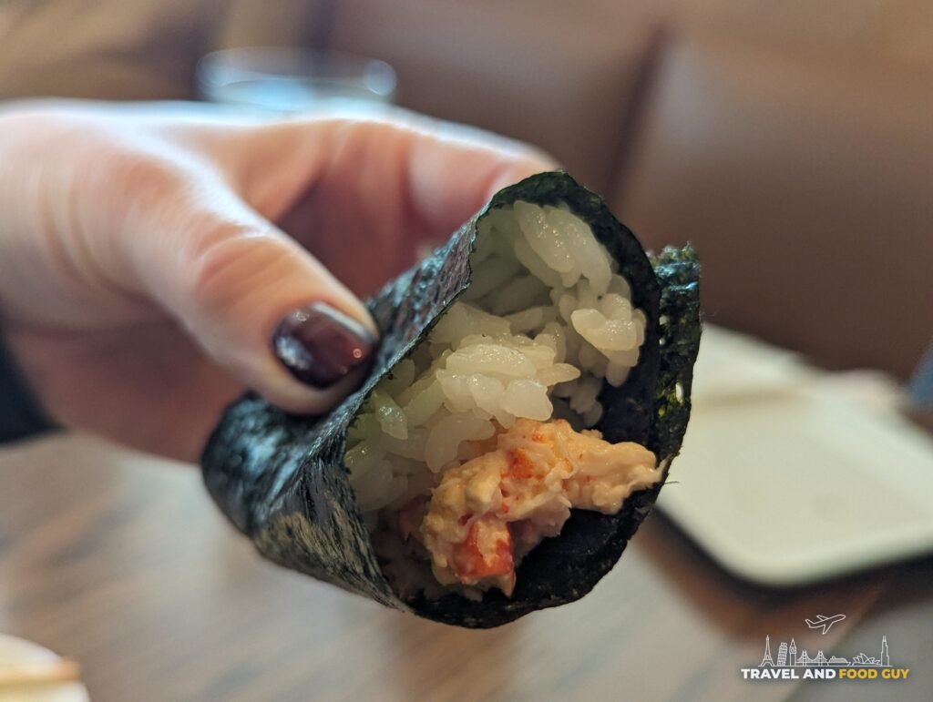 Vika holding a SUGARFISH lobster hand roll, with warm rice and chunks of lobster in a creamy dressing, at SUGARFISH Beverly Hills.
