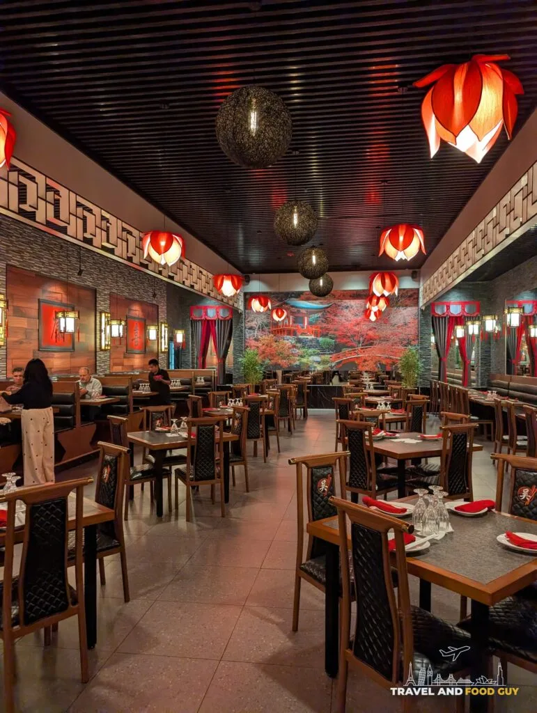 Rows of empty wooden tables under red lanterns in the sushi side dining room at Wu's House Kildeer.