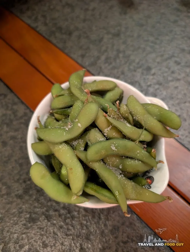 A white bowl of salted edamame on the table at Wu's House Kildeer.