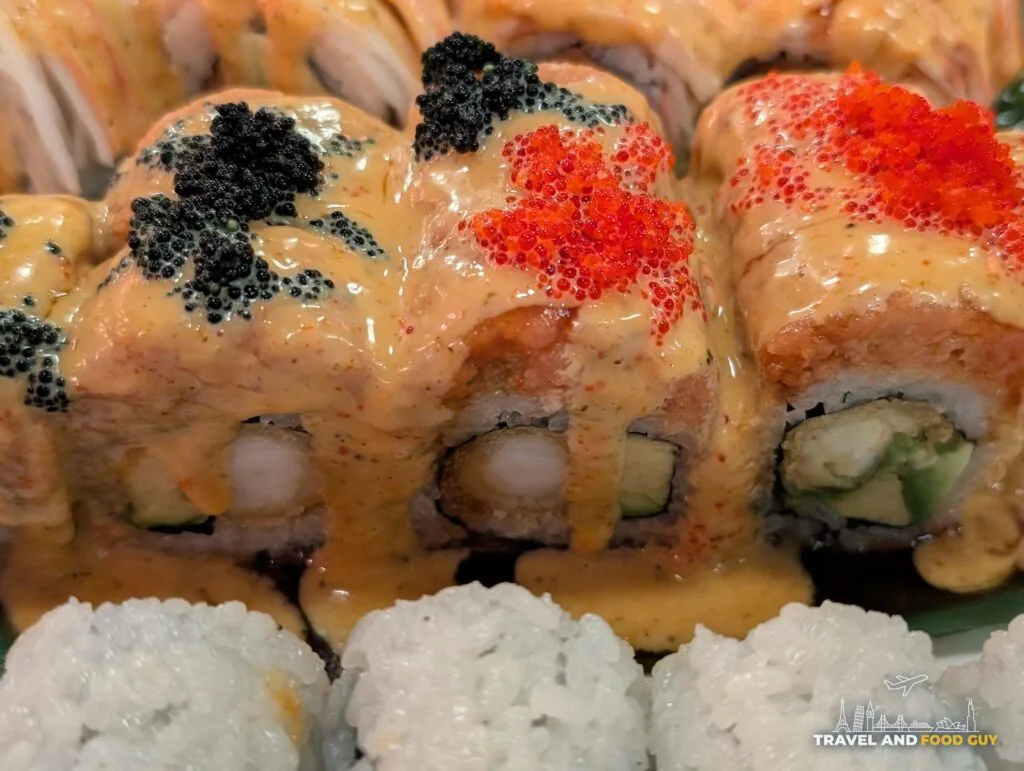 Black Thunder Roll pieces at Wu's House topped with black and red tobiko and covered in sauce, shrimp tempura and avocado inside.