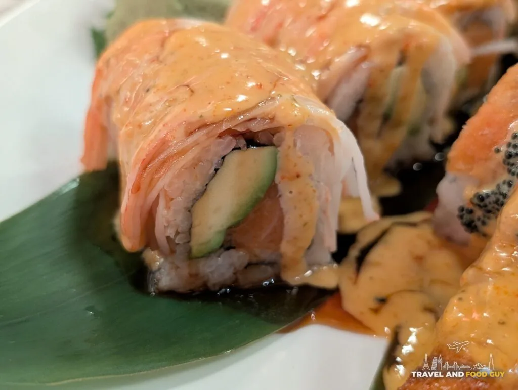 A close up of the SK Bomb Roll at Wu's House Kildeer, avocado inside, shrimp on top and spicy mayo and eel sauce poured over.